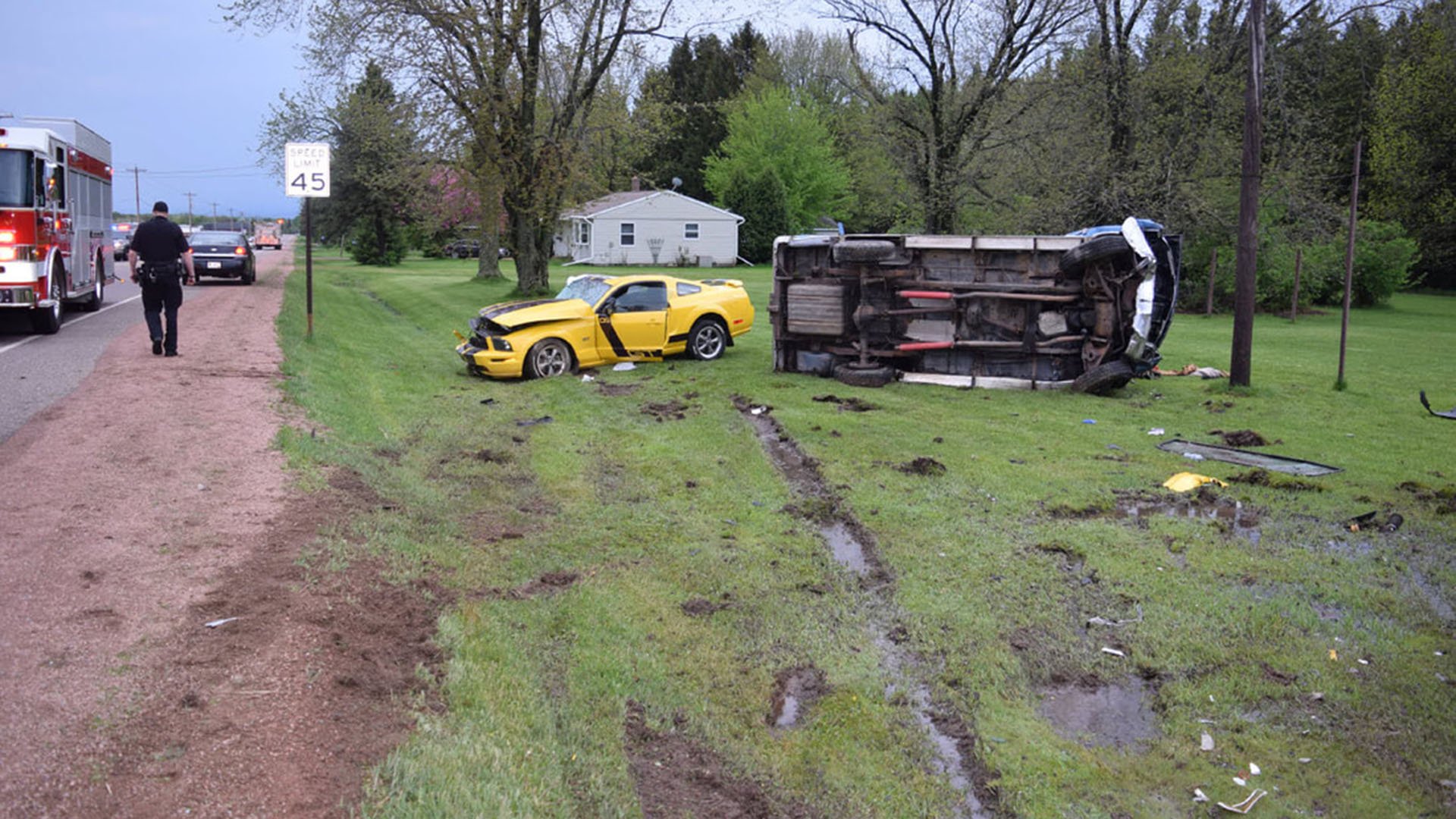 yellow sports car and overturned semi in ditch