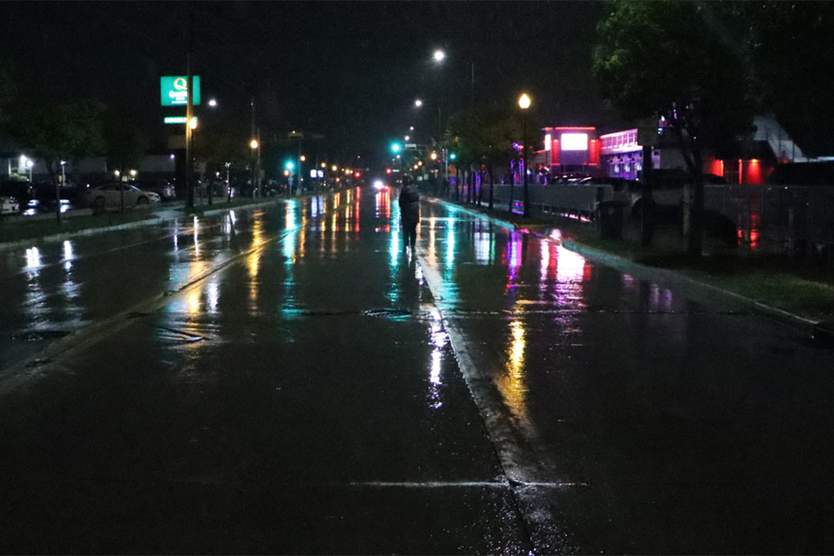 person standing on busy street at night in the rain